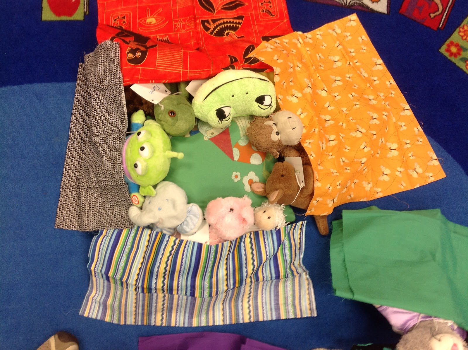 Stuffed animals under a blanket having a sleepover at the library.