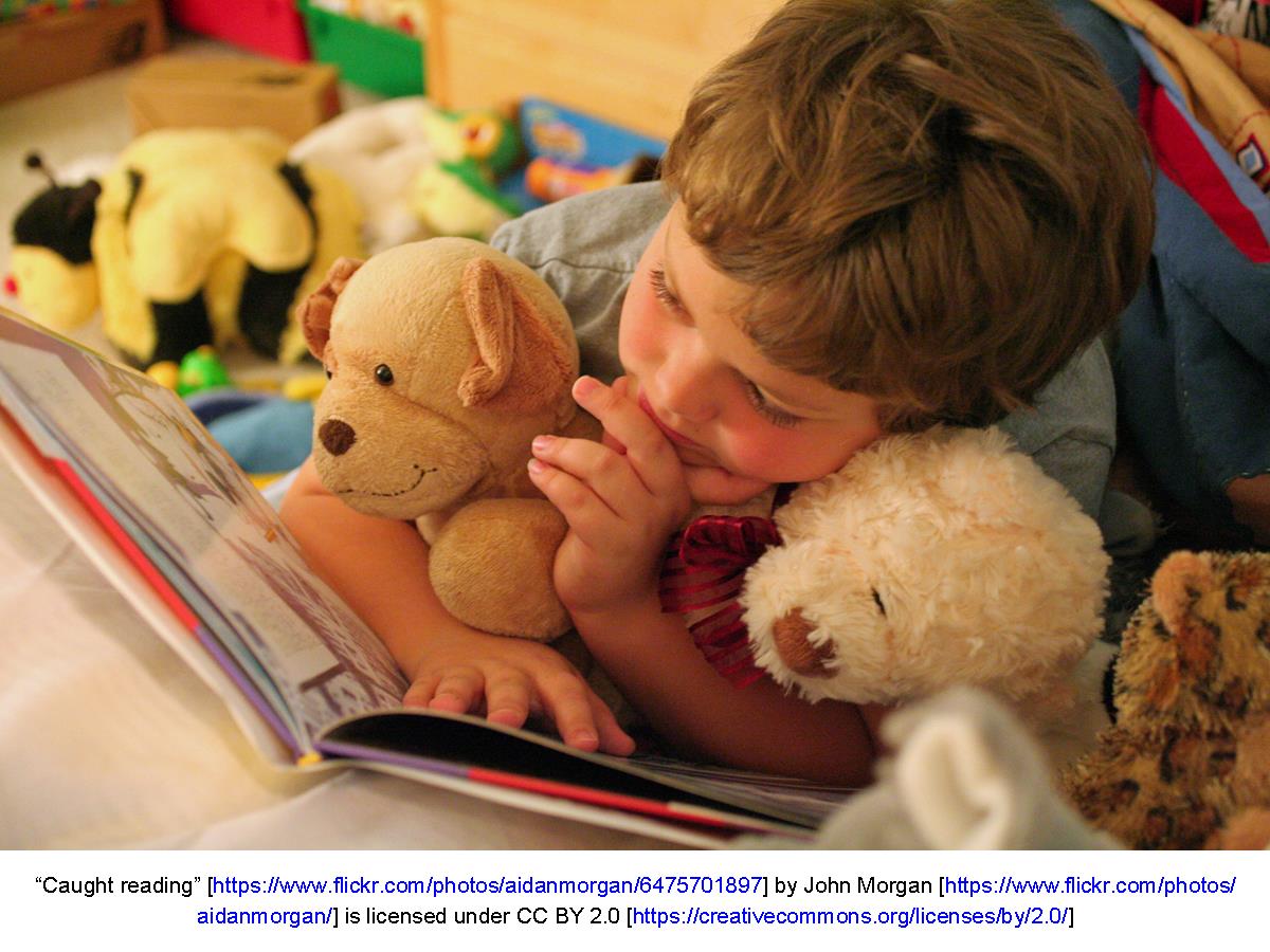 Child looking at book surrounded by toys