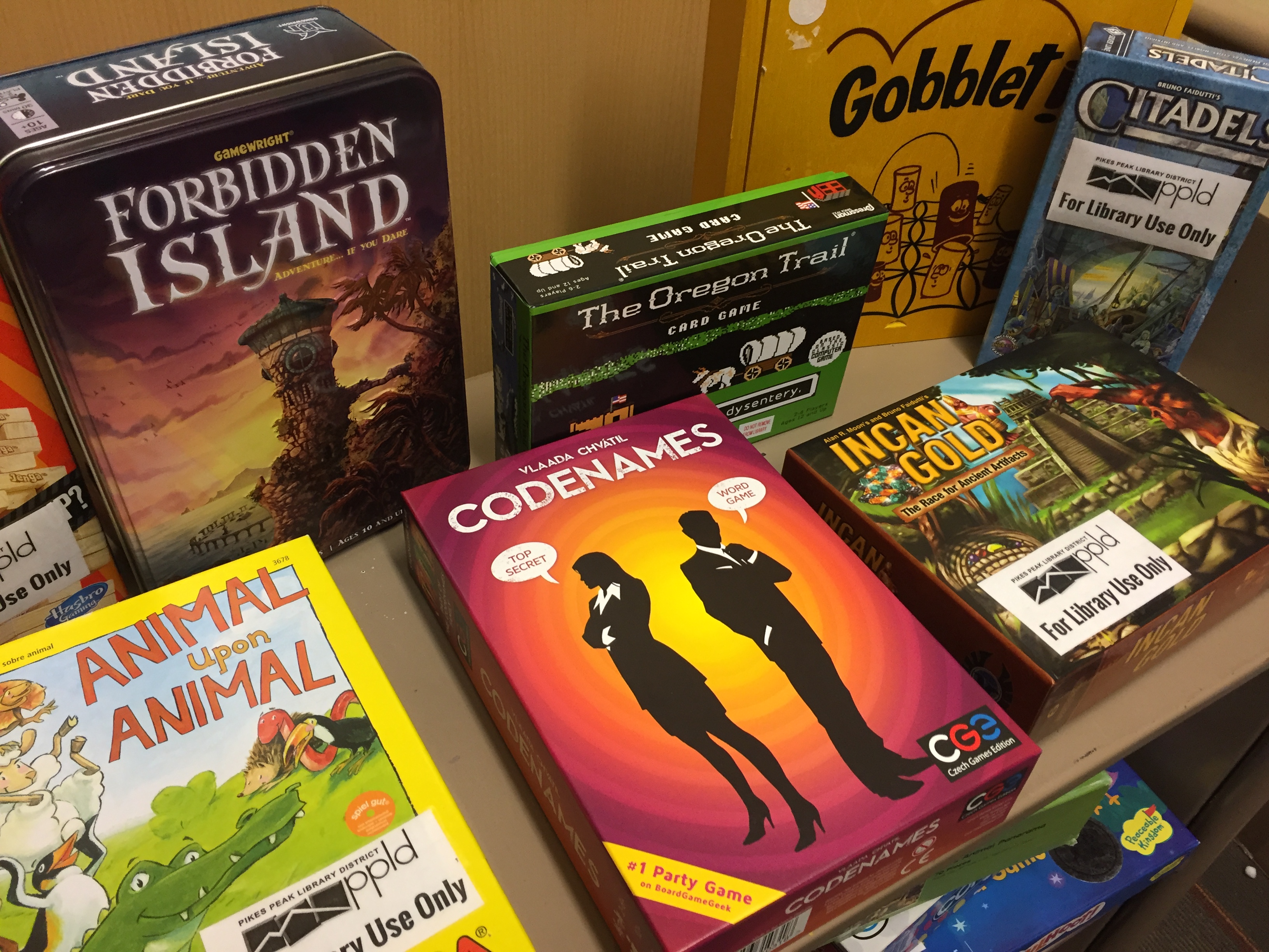 Board games on a cart including Codenames, Forbidden Island, Animal Upon Animal, Citadel, Incan Gold