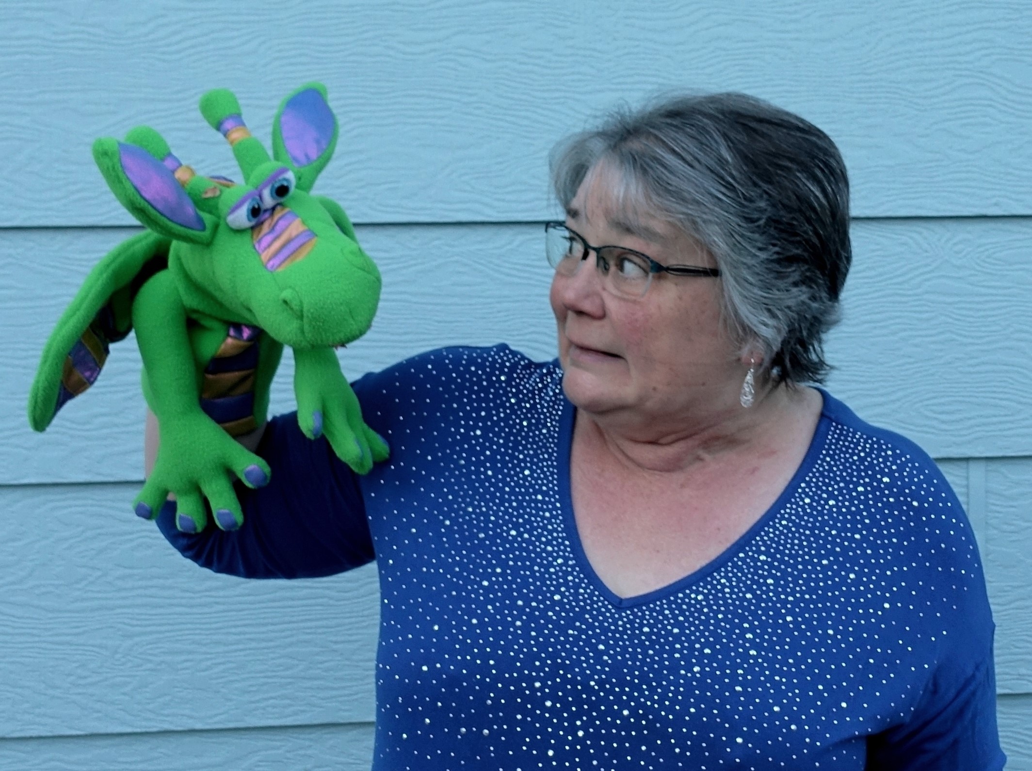 person holding green dragon puppet