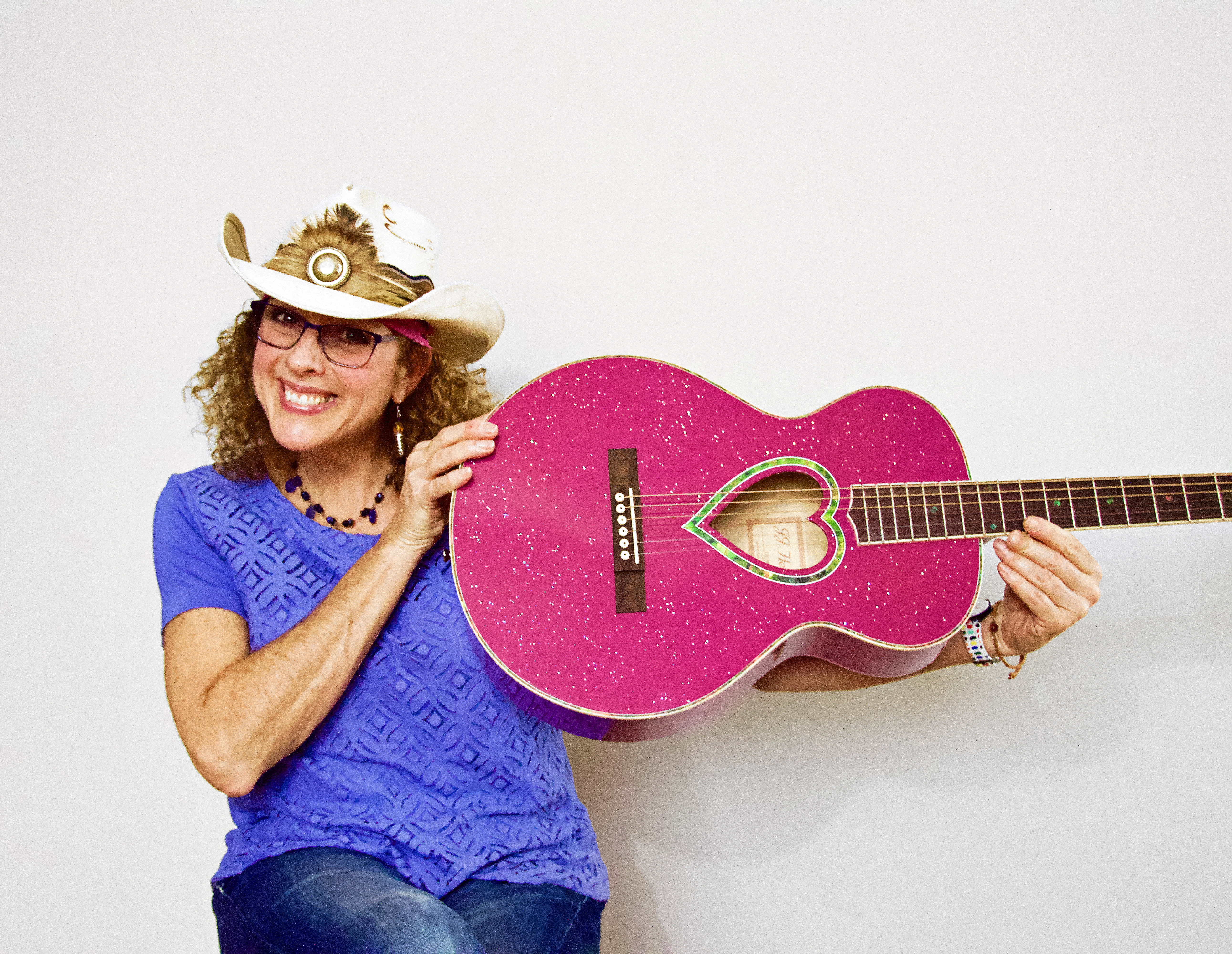 Woman in cowboy hat holding pink guitar