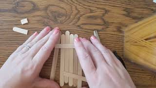 Close-up of person assembling door out of popsicle sticks.