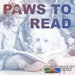 This promotional image includes a photograph of a young child with a book open on their lap, reading a book to a white dog. On top of the image is the name of the program, "Paws to Read", with the Pikes Peak Library District logo in the bottom right corner. 