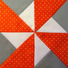 A double pinwheel quilt block made using white, gray and red polka dot fabric