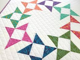 A quilt with a white background and Friendship Star quilt blocks in various bright colors