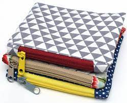 Three zippered pouches in various colors sit in a stack