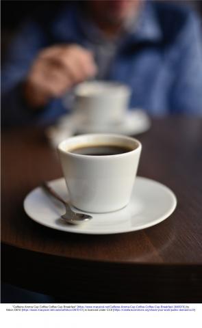 Coffee mug on a table with person sitting across from viewer