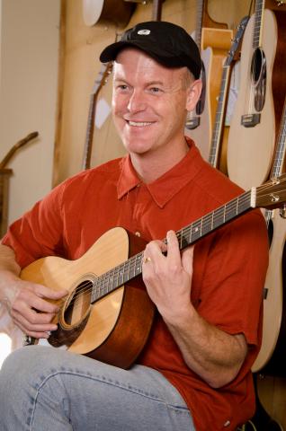 Man in baseball cap playing guitar.