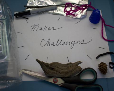 Assorted crafting materials laid out as a frame around piece of paper with the text "Maker Challenges"