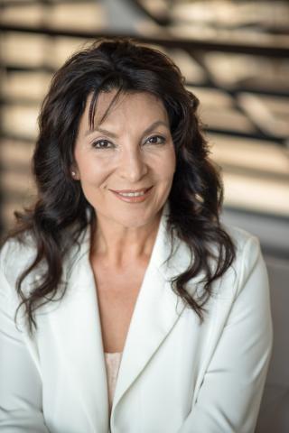 Nohemy Montes, a woman with dark hair wearing a white suit