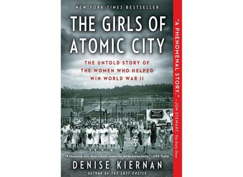 Cover of the book The Girls of Atomic City by Denise Kiernan. It shows a greyscale image of a large group of women coming toward the camera with a city behind them.