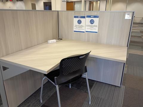 Charging cubicle with L-shaped desk, two privacy walls, and one chair.